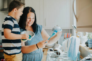 Mother teaching son how to wash the dishes