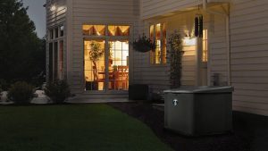 Home at night lit from within with generator out front