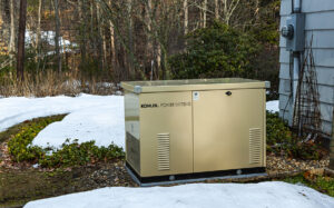 Whole house generator installed on a concrete pad outside a house. There's snow on the ground.